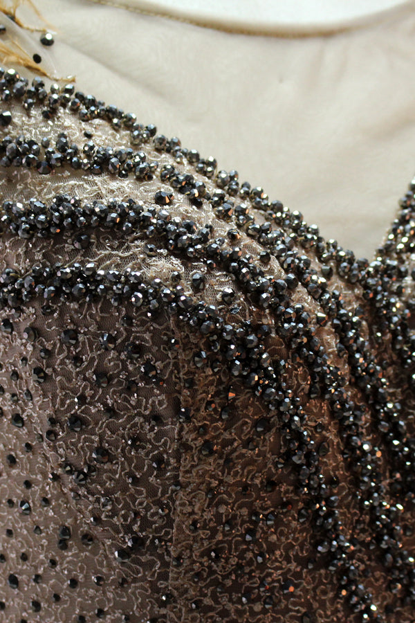 Displayed on a mannequin is a light - green evening gown. It features a sheer neckline with feather and bead embellishments, and a voluminous, glittering skirt. The elegant design creates a dreamy and luxurious look, perfect for formal events.4