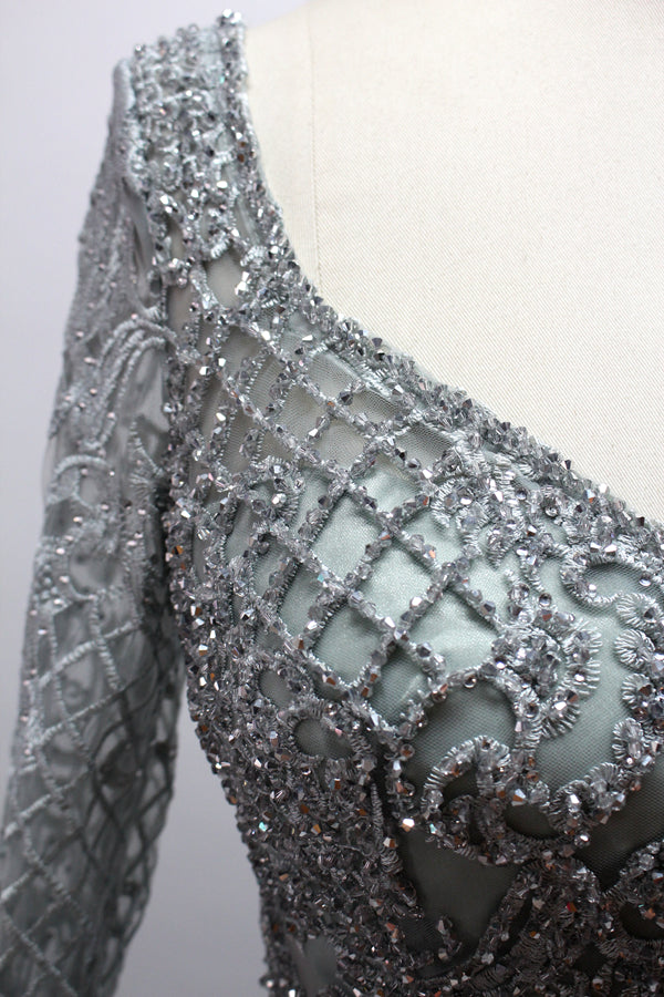 Showcased on a mannequin is a silver - gray evening gown. It has a V - neckline, long sleeves, and intricate lace embroidery all over. The elaborate design gives off a luxurious and elegant vibe, ideal for formal occasions.8