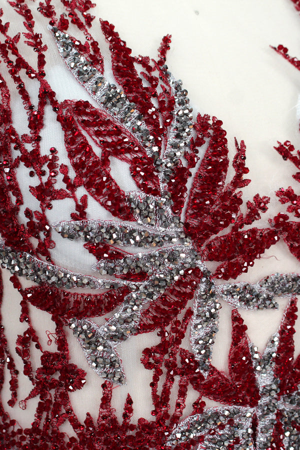 Presented on a mannequin is a gown with a gray base and rich red floral embroidery. It features a sheer neckline, a sleeveless design, and an intricate pattern that gives off a romantic and elegant vibe, perfect for formal events.5