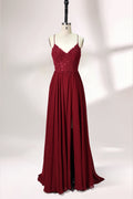 Displayed on a mannequin is a burgundy gown. It features spaghetti straps, a lace - adorned bodice, and a flowing chiffon skirt with a slit. The elegant design suits formal events like galas or weddings.1