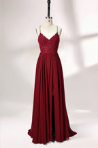 Displayed on a mannequin is a burgundy gown. It features spaghetti straps, a lace - adorned bodice, and a flowing chiffon skirt with a slit. The elegant design suits formal events like galas or weddings.1
