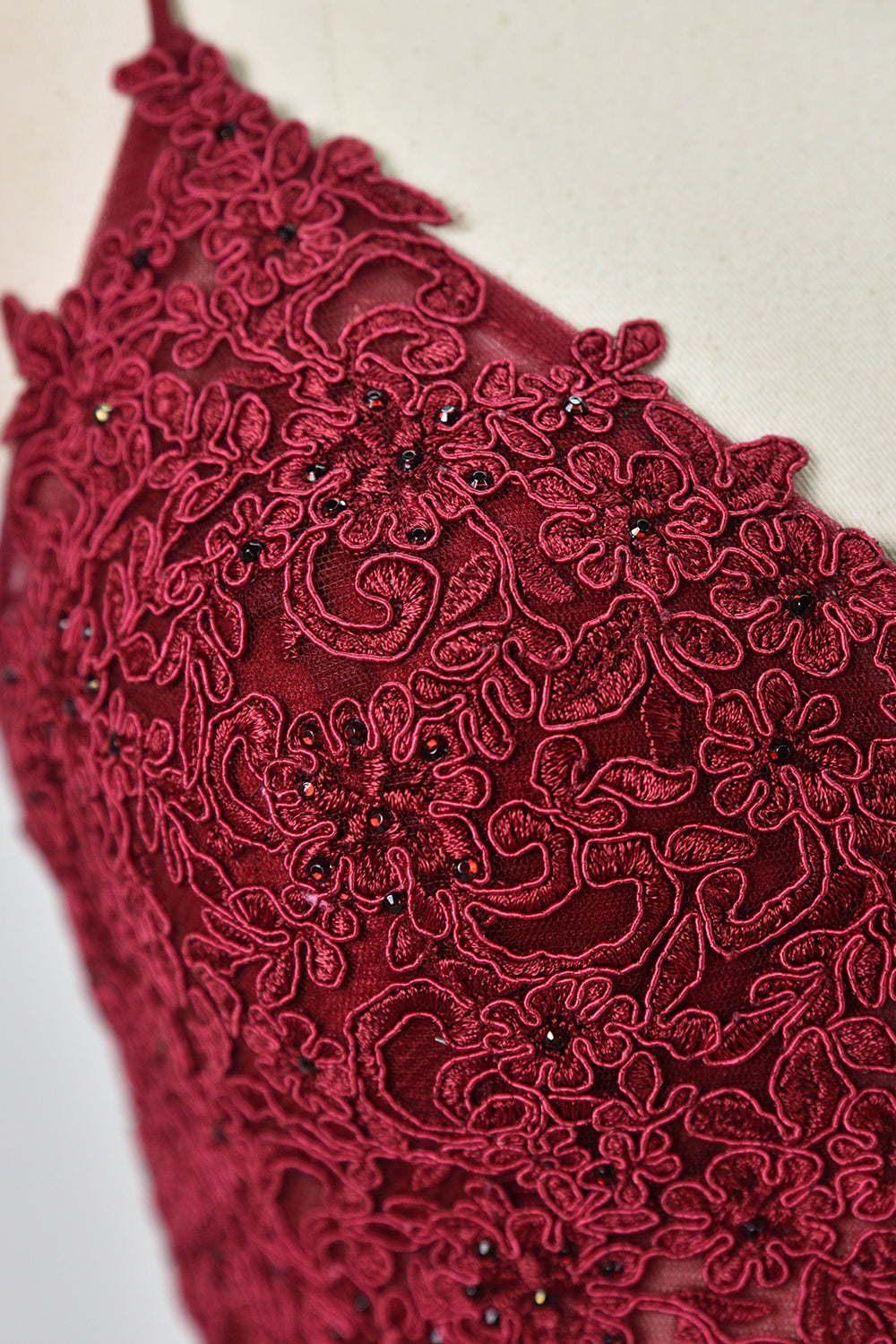 Displayed on a mannequin is a burgundy gown. It features spaghetti straps, a lace - adorned bodice, and a flowing chiffon skirt with a slit. The elegant design suits formal events like galas or weddings.6