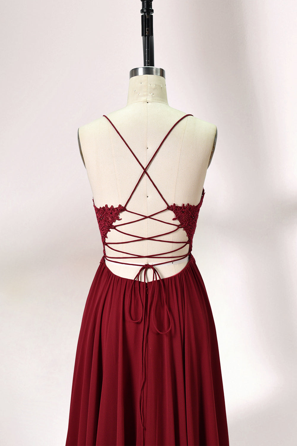 Displayed on a mannequin is a burgundy gown. It features spaghetti straps, a lace - adorned bodice, and a flowing chiffon skirt with a slit. The elegant design suits formal events like galas or weddings.2