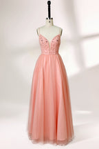 Photograph of a mannequin wearing an elegant, floor-length, blush pink tulle gown with a fitted bodice adorned with sequin embellishments and thin spaghetti straps. The gown has a sweetheart neckline and a full skirt with a subtle sparkle, creating a soft, ethereal effect. The background is a plain white studio setting with soft lighting casting gentle shadows.01
