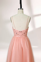 Photograph of a mannequin wearing an elegant, floor-length, blush pink tulle gown with a fitted bodice adorned with sequin embellishments and thin spaghetti straps. The gown has a sweetheart neckline and a full skirt with a subtle sparkle, creating a soft, ethereal effect. The background is a plain white studio setting with soft lighting casting gentle shadows.05