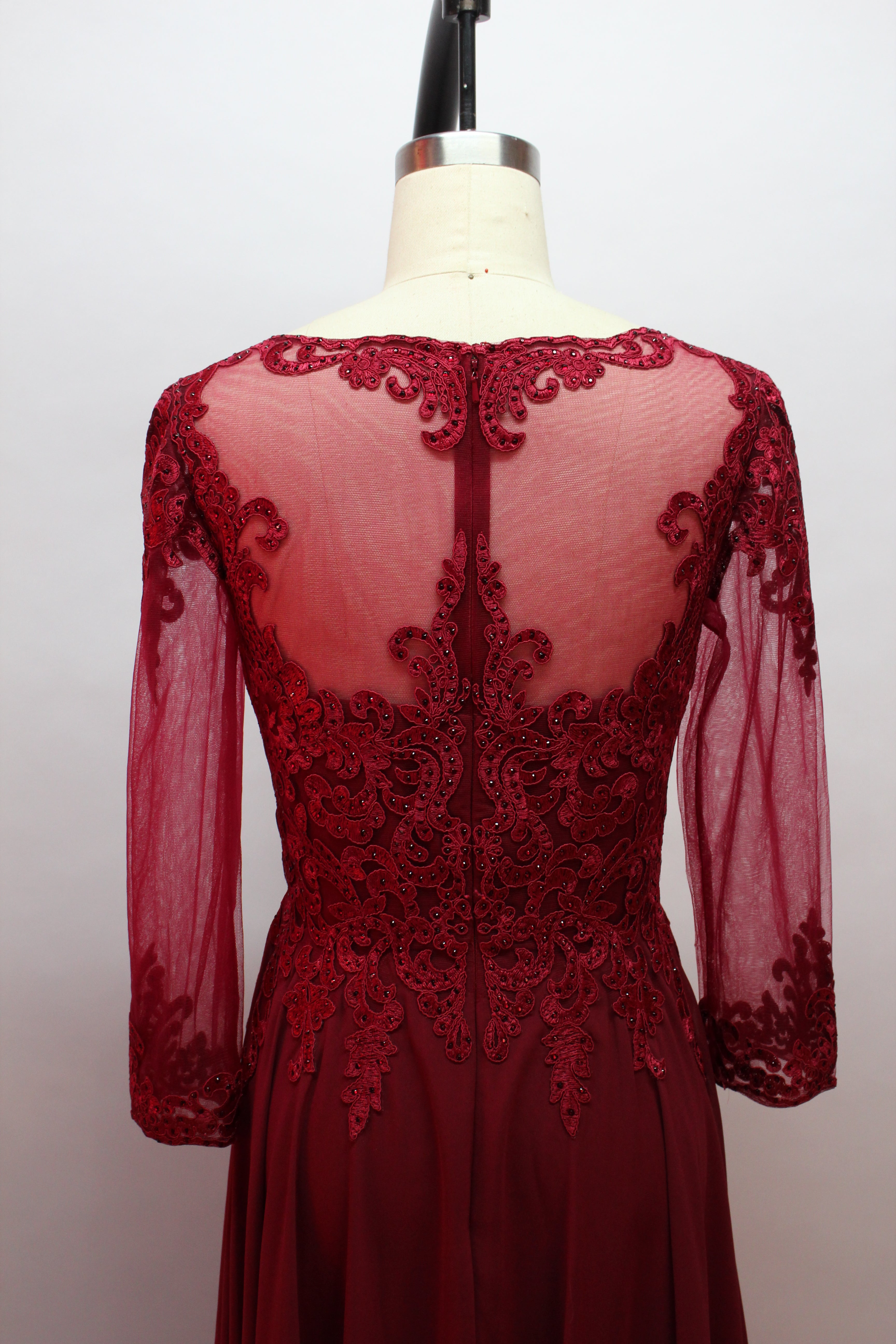 Front view of an elegant burgundy A-line mother of the bride dress featuring a scoop neck bodice with intricate beaded lace detailing, sheer long chiffon sleeves, and a long flowing floor-length chiffon skirt, suitable for weddings and formal evening galas and available for wholesale or bulk purchase.