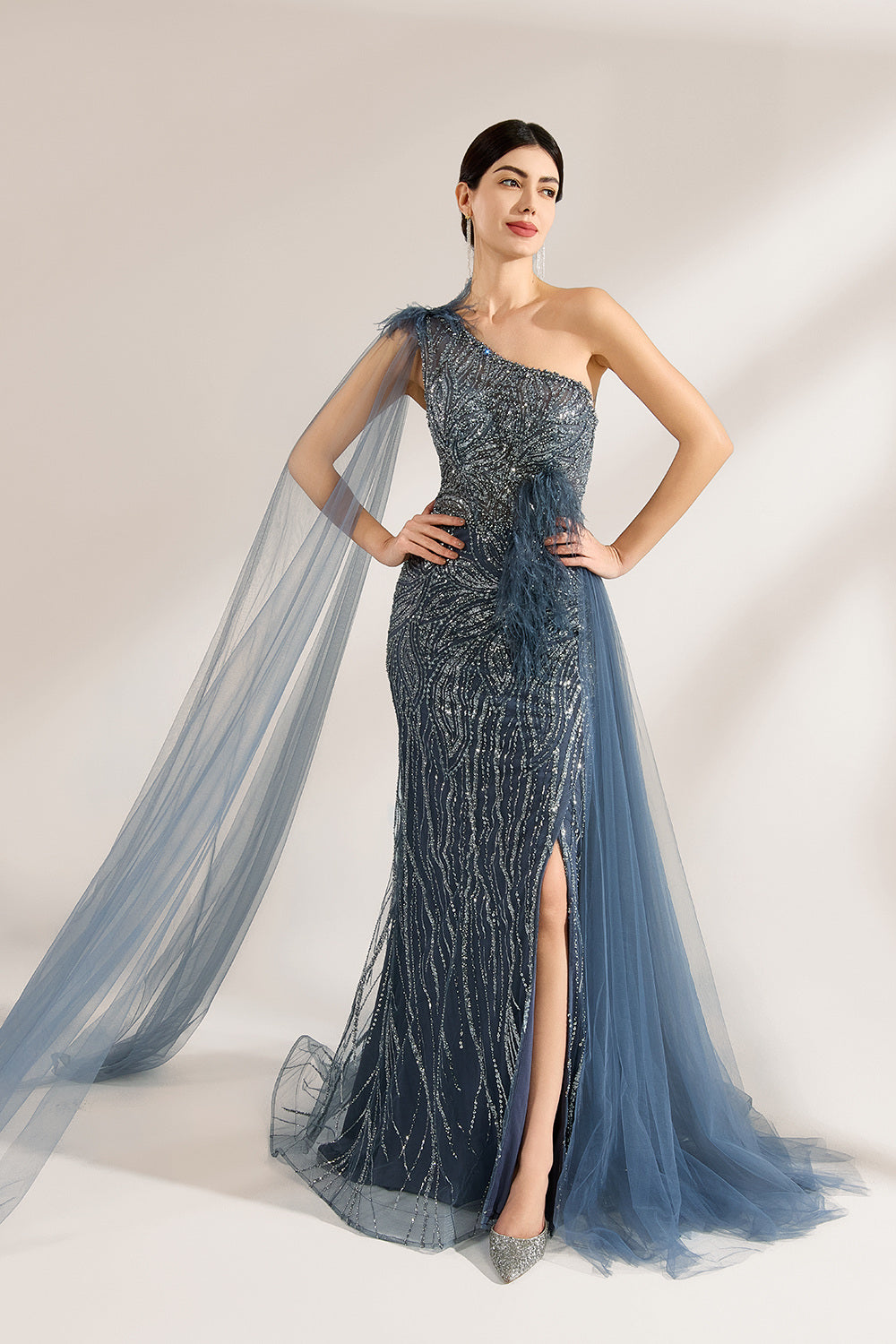 Bathed in soft light, a woman graces the scene in a navy - blue sequined one - shoulder gown. It’s adorned with feather details, a flowing tulle cape, and a high side slit. The mermaid silhouette, shimmering with sequins, exudes opulence, perfect for grand galas or red - carpet moments.1