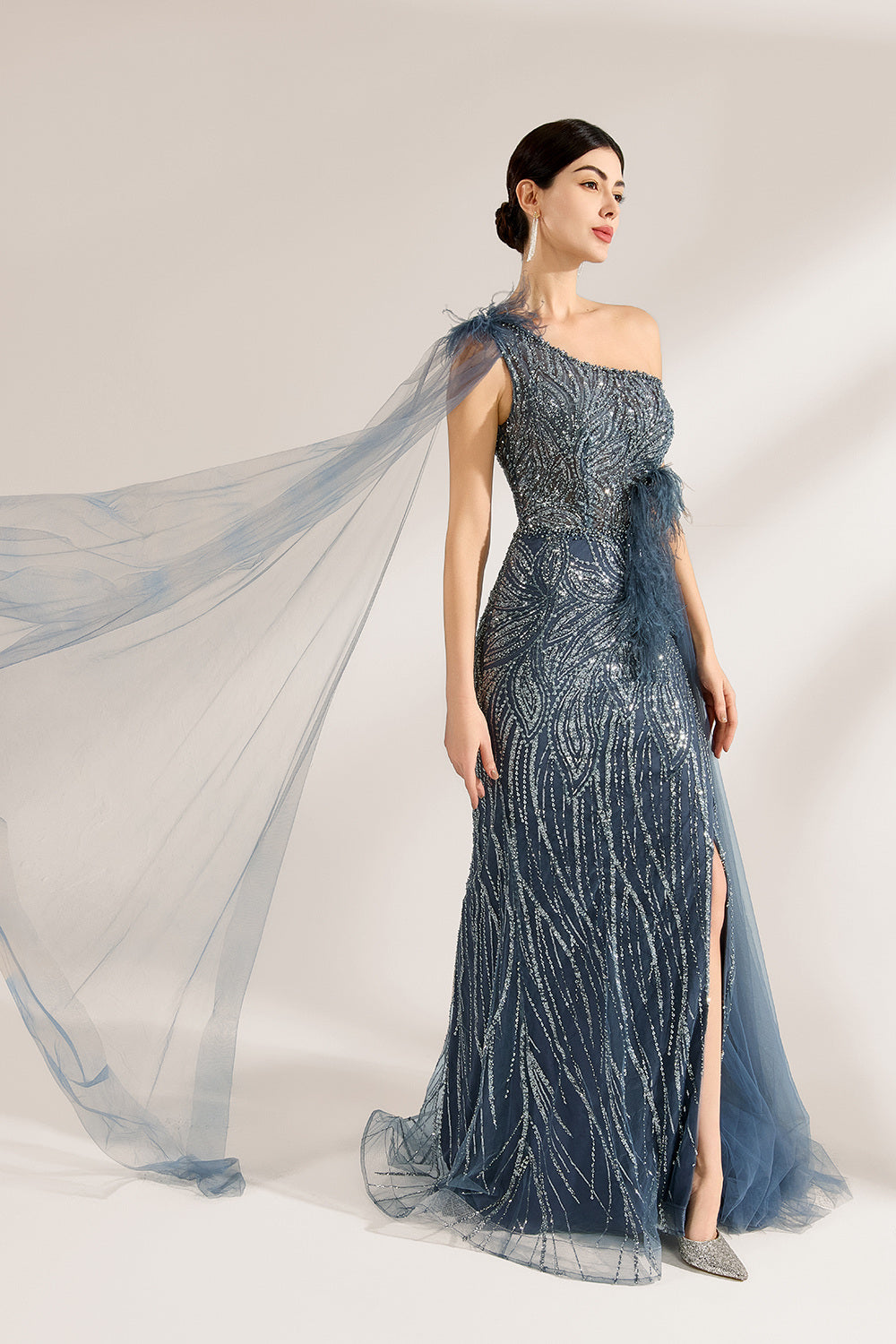 Bathed in soft light, a woman graces the scene in a navy - blue sequined one - shoulder gown. It’s adorned with feather details, a flowing tulle cape, and a high side slit. The mermaid silhouette, shimmering with sequins, exudes opulence, perfect for grand galas or red - carpet moments.2