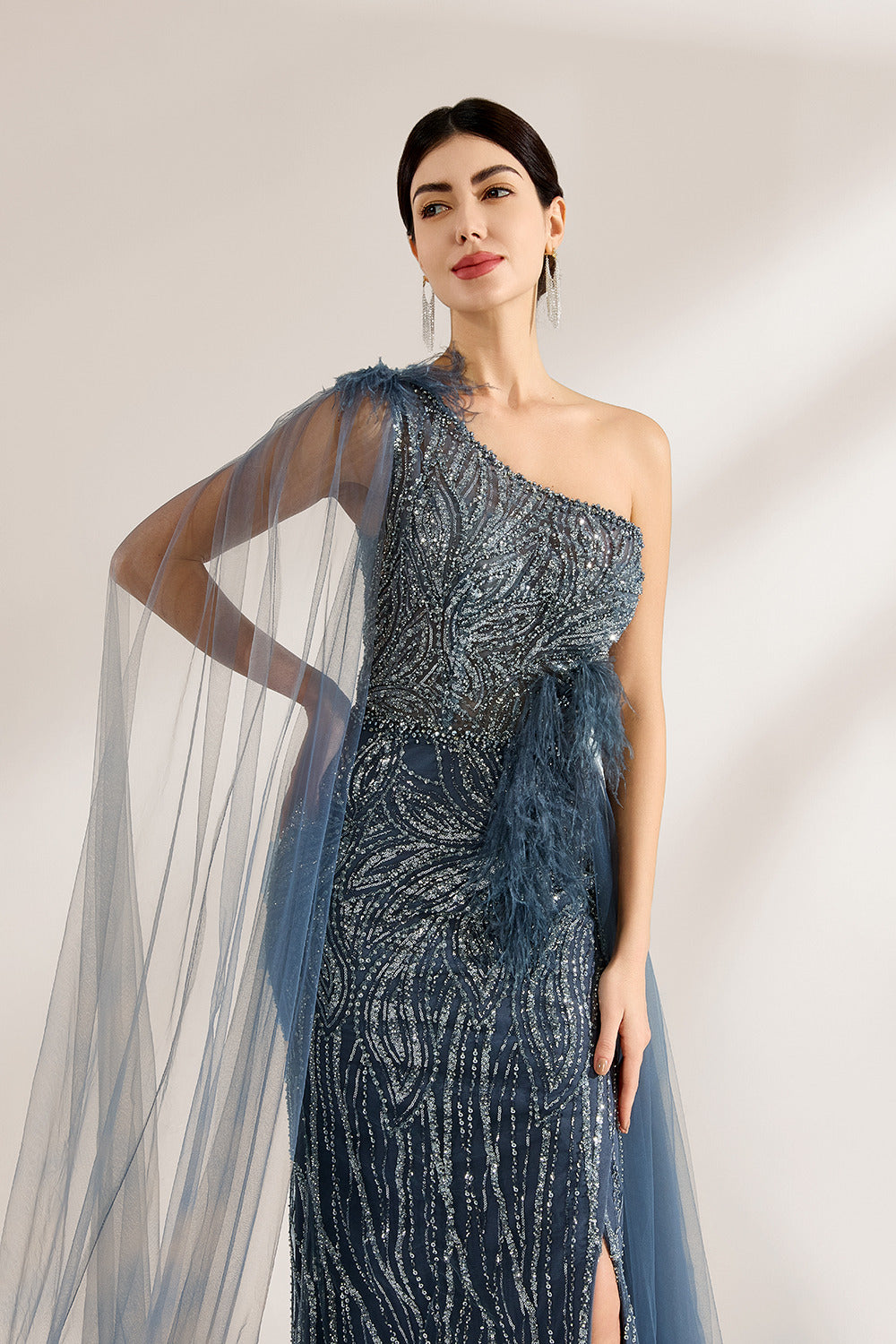 Bathed in soft light, a woman graces the scene in a navy - blue sequined one - shoulder gown. It’s adorned with feather details, a flowing tulle cape, and a high side slit. The mermaid silhouette, shimmering with sequins, exudes opulence, perfect for grand galas or red - carpet moments.3