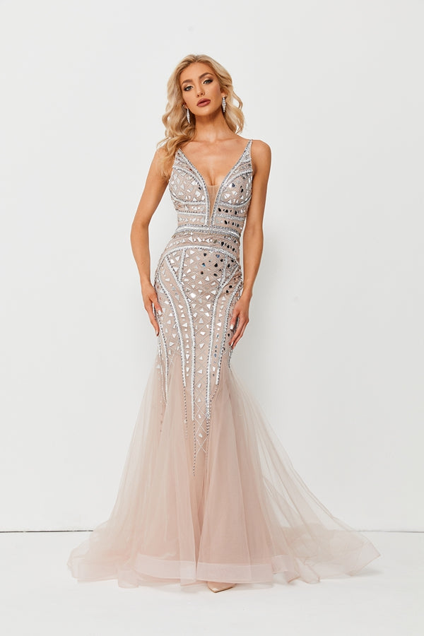 Beautiful blonde woman, long wavy hair, wearing elegant floor-length gown, silver and crystal embellishments, sheer tulle skirt, slim figure, fair skin, standing against plain white background, elegant pose, arms raised, closed eyes, makeup with smoky eyes, full lips, glamorous, sophisticated, fashion photography, high-fashion, luxury, evening gown, soft lighting, minimalistic background, studio shot